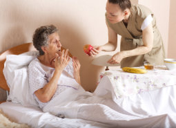 caregiver serving a senior in bed