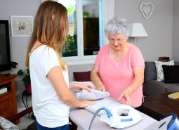 young woman helping a senior iron some garments