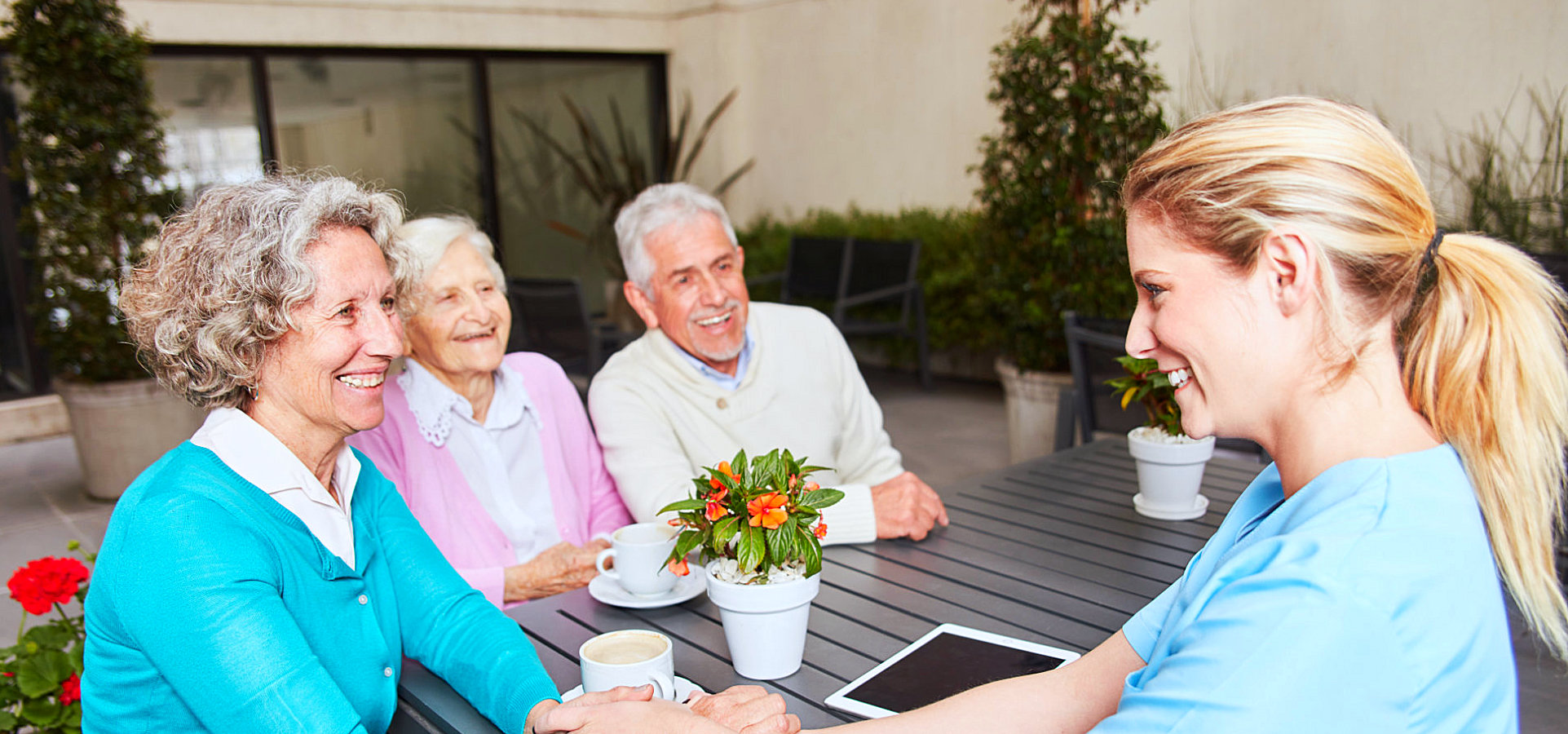 three seniors having a coffee with a caregiver